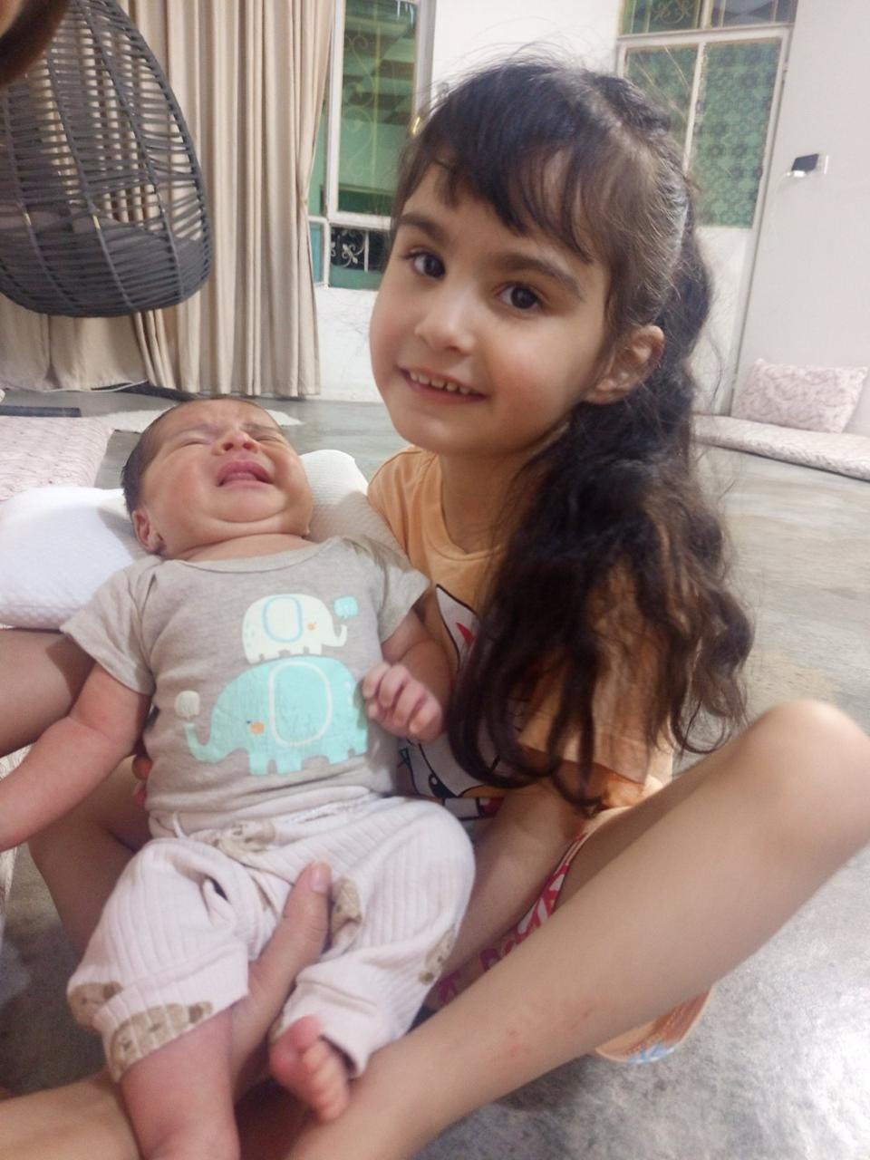 Maria holding her newborn baby brother Nazar in her lap.