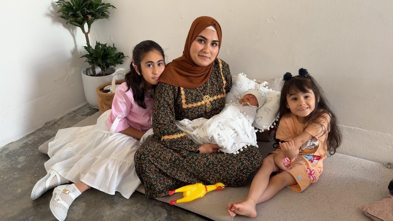 Nazar's mother holds him while his sisters sit close beside her.